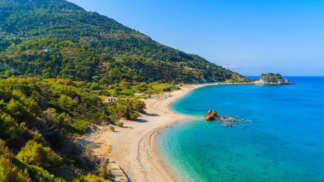 Κατάφυτη με ζαφειρένια νερά: Το ελληνικό νησί με μία από τις πιο εντυπωσιακές παραλίες του Αιγαίου