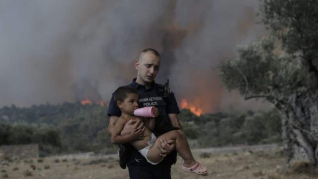 Όλη η Ευρώπη μιλάει για τις φωτιές στην Ελλάδα: Μονοπωλεί τα πρωτοσέλιδα ο αστυνομικός με το παιδί αγκαλιά γύρω από τις φλόγες (photos)