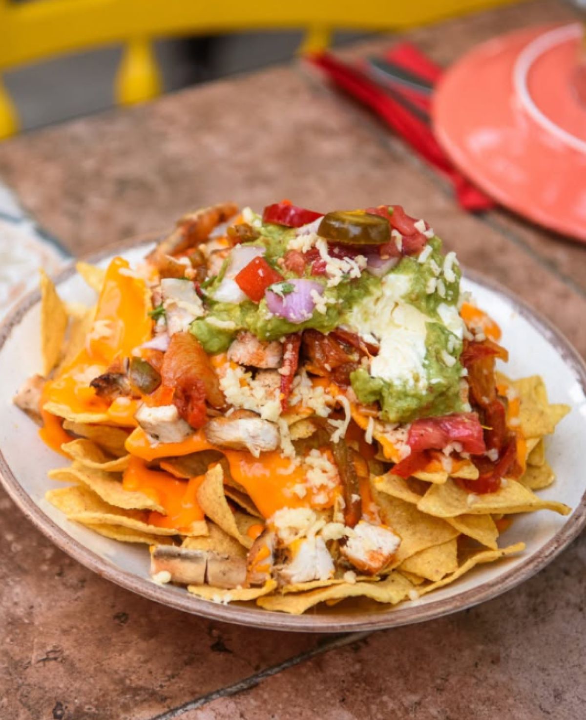 Ένα μεγάλο μπολ με τραγανά nachos, συνοδευόμενο από μπολάκια με guacamole και κόκκινη μεξικάνικη σάλτσα πάνω σε ξύλινο τραπέζι