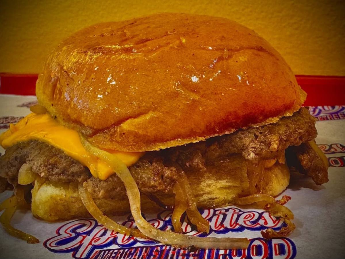 Ένα ζουμερό smash burger με διπλό μπιφτέκι, καλυμμένο ολοκληρωτικά από ρευστό κίτρινο τσένταρ