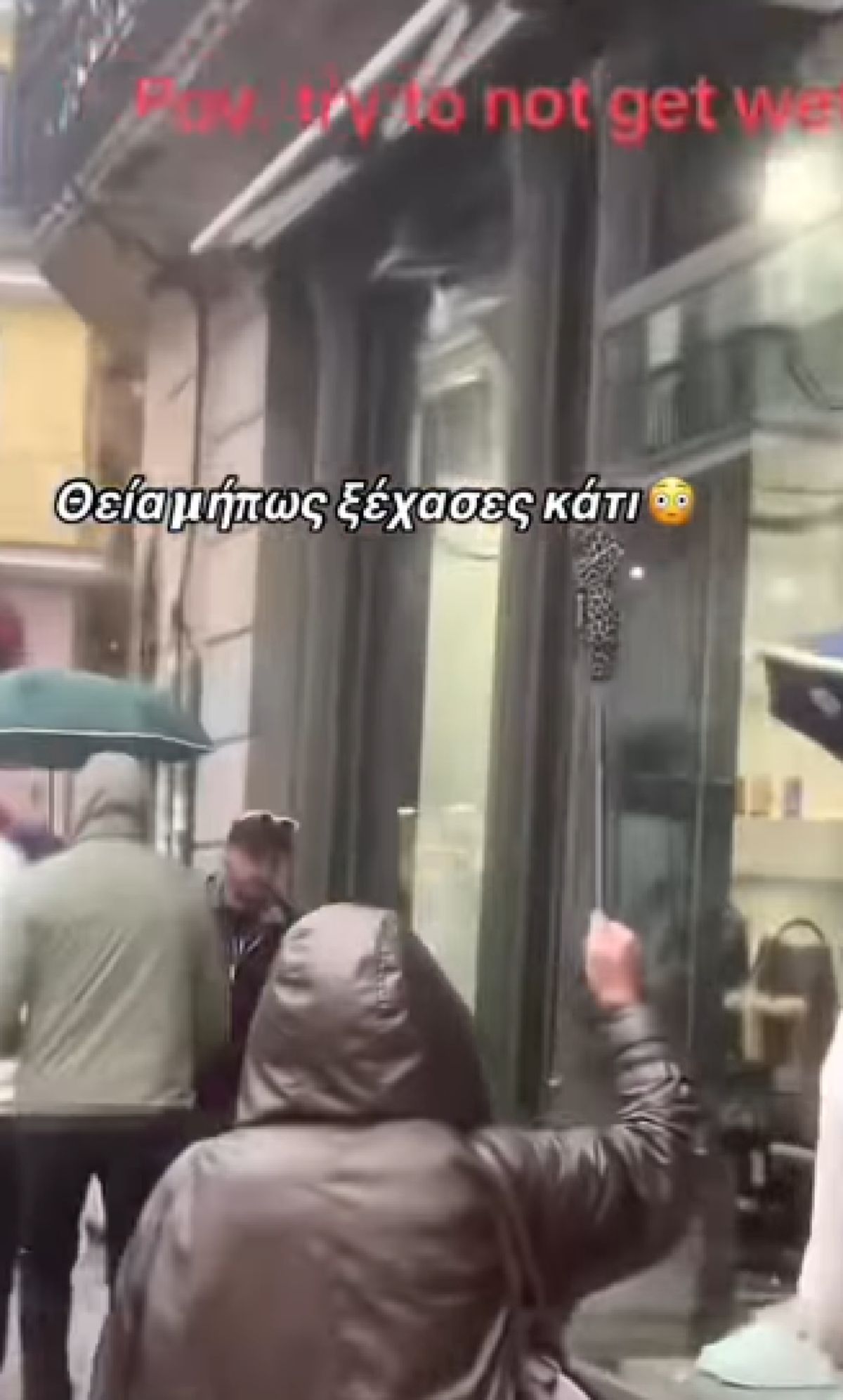 Κοντινό πλάνο μιας κλειστής ομπρέλας που την κρατάει ένα χέρι ψηλά κόντρα στον γκρίζο και βροχερό ουρανό της πόλης