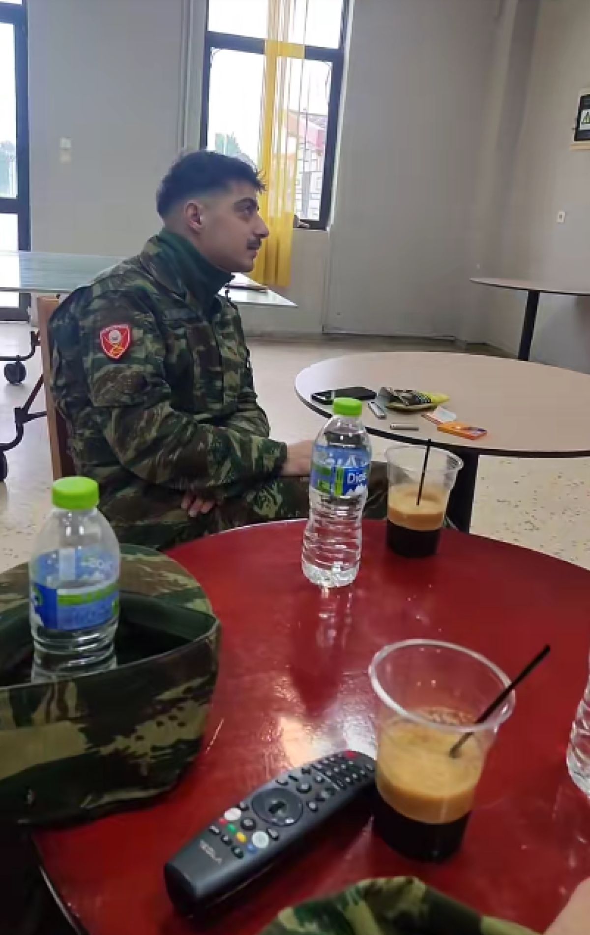Εσωτερικός χώρος στρατιωτικού κυλικείου (ΚΨΜ) με τραπέζια, καρέκλες και μια τηλεόραση στον τοίχο