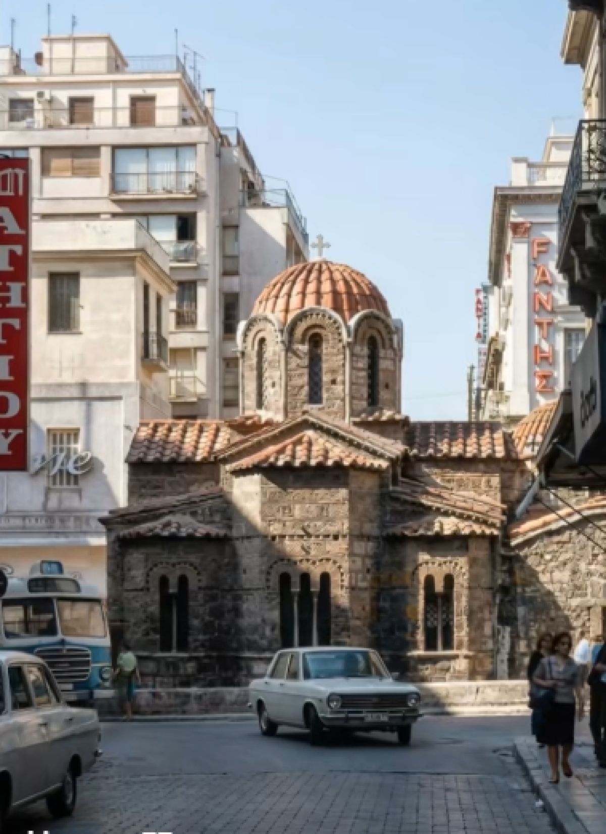 Νυχτερινή ή απογευματινή λήψη της Ομόνοιας με φωτισμένες πινακίδες καταστημάτων και κινηματογράφων της εποχής