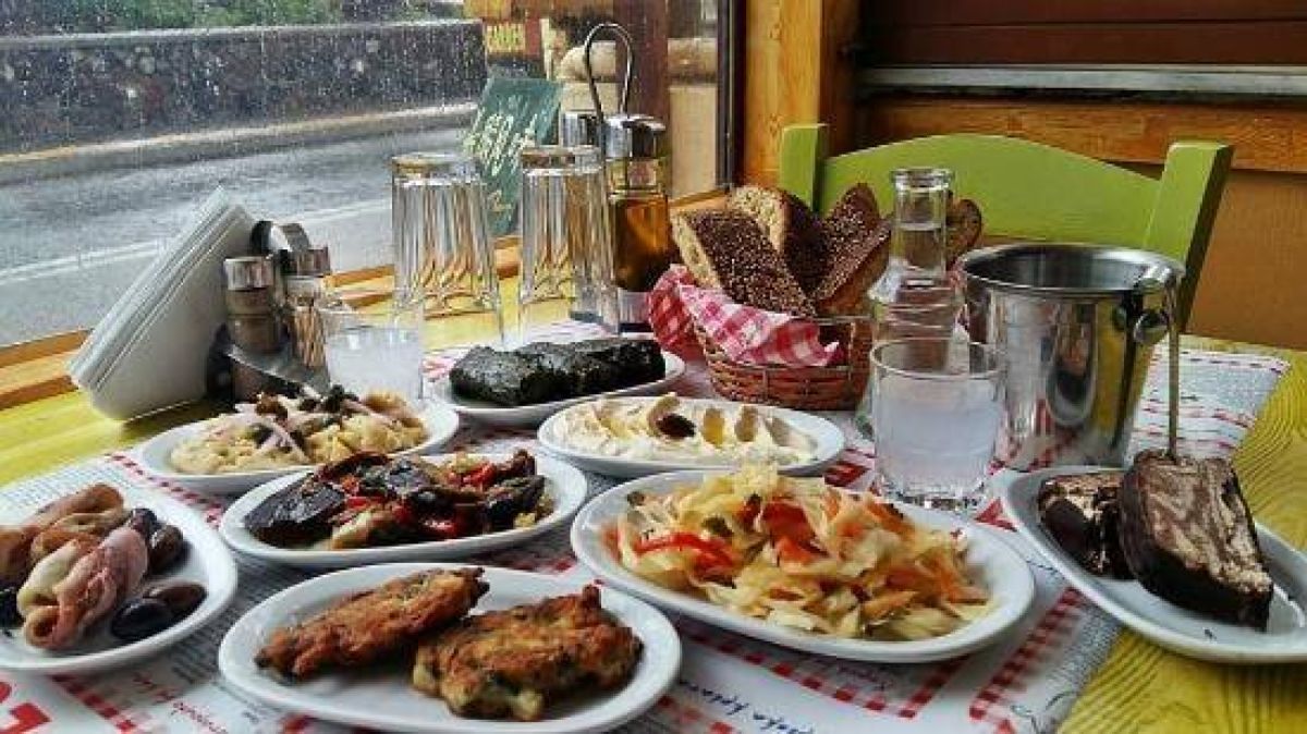 Πλούσιο τραπέζι γεμάτο με κρητικούς μεζέδες, ντάκο, καπνιστά κρέατα και μικρά πιάτα, σερβιρισμένα με παραδοσιακό τρόπο