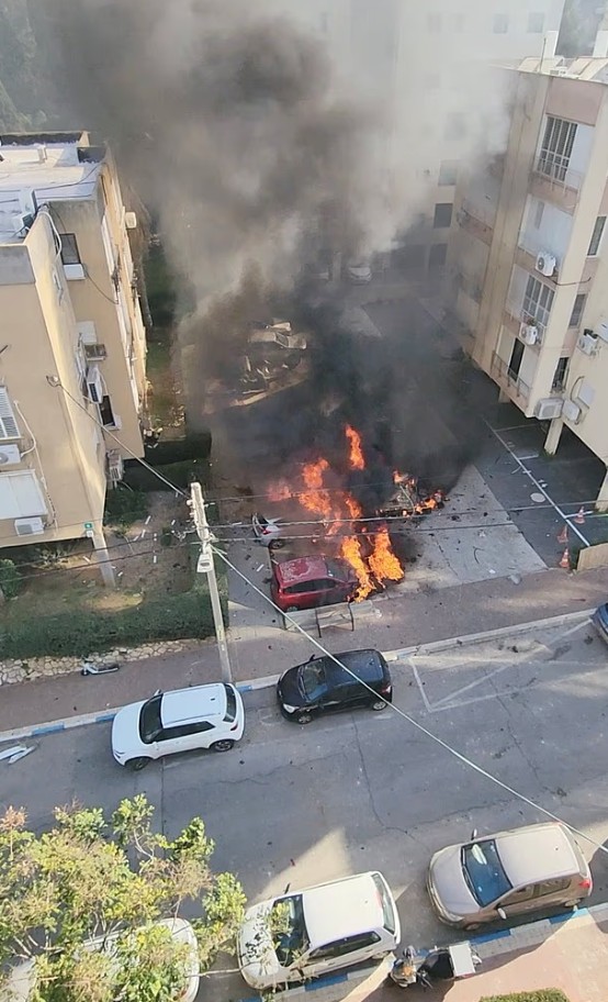 Καπνός και φλόγες αναδύονται από οχήματα μετά την πτώση θραυσμάτων από ιρανική πυραυλική επίθεση σε χώρο στάθμευσης, στο Ραμάτ Γκαν του Ισραήλ.