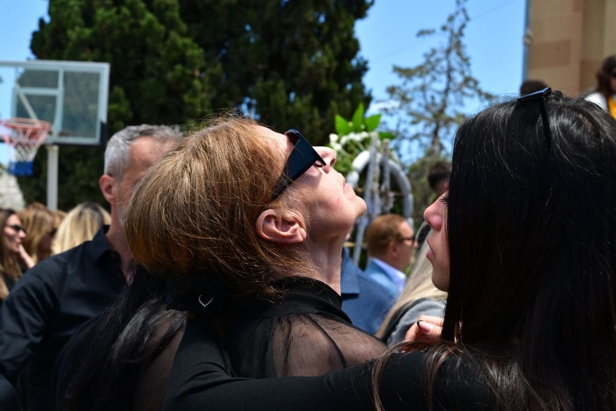 Η μητέρα της Γωγώς Μαστροκώστα κρατά τη φωτογραφία της κόρης της και κοιτάζει τον ουρανό.